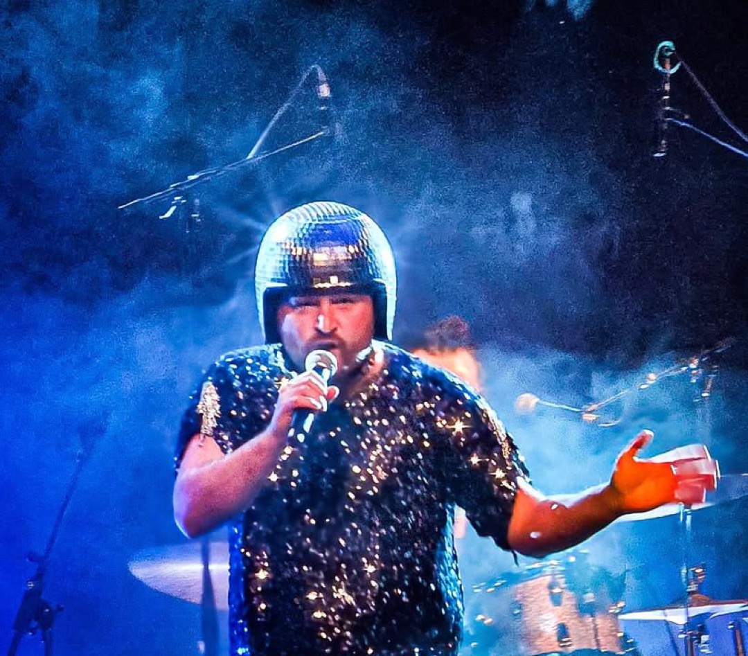 Gitarrist der Band spielt konzentriert im bunten Bühnenlicht.